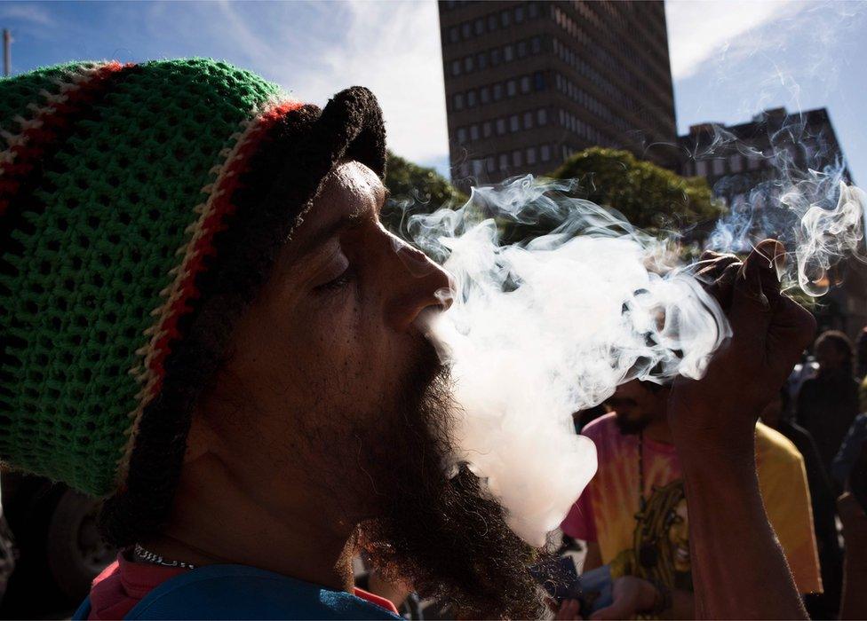 A man smokes marijuana out of a bottle-neck pipe, joining about 1500 people as they protest in front of the parliament in Cape Town, South Africa - 5 May 2018