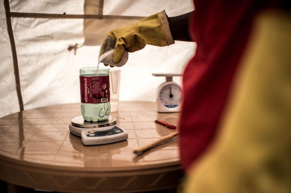 A lab assistant weighs out a measure of chlorine powder