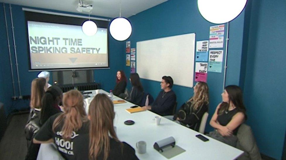 Students gathered around a table watching the safety film