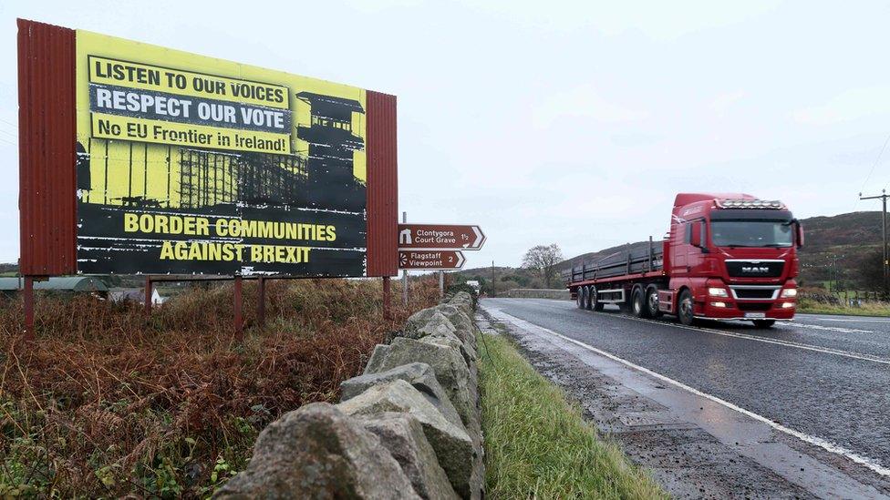 A lorry travels past a sign protesting against a hard border in Ireland