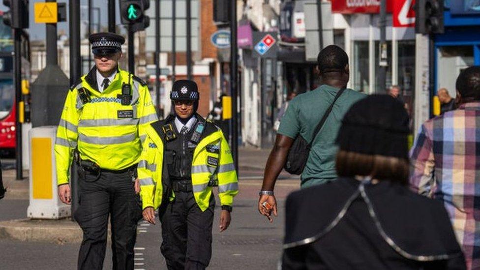 Police officers patrol through Stamford Hill, an area of London with a large Jewish community, on 10 October