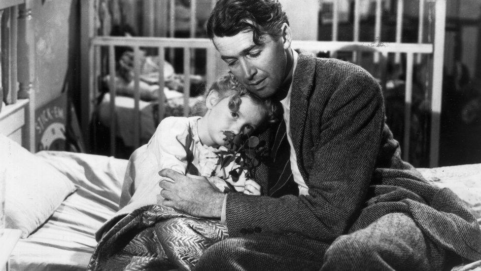 American actor James Stewart as George Bailey, hugs actor Karolyn Grimes, who plays Zuzu his daughter