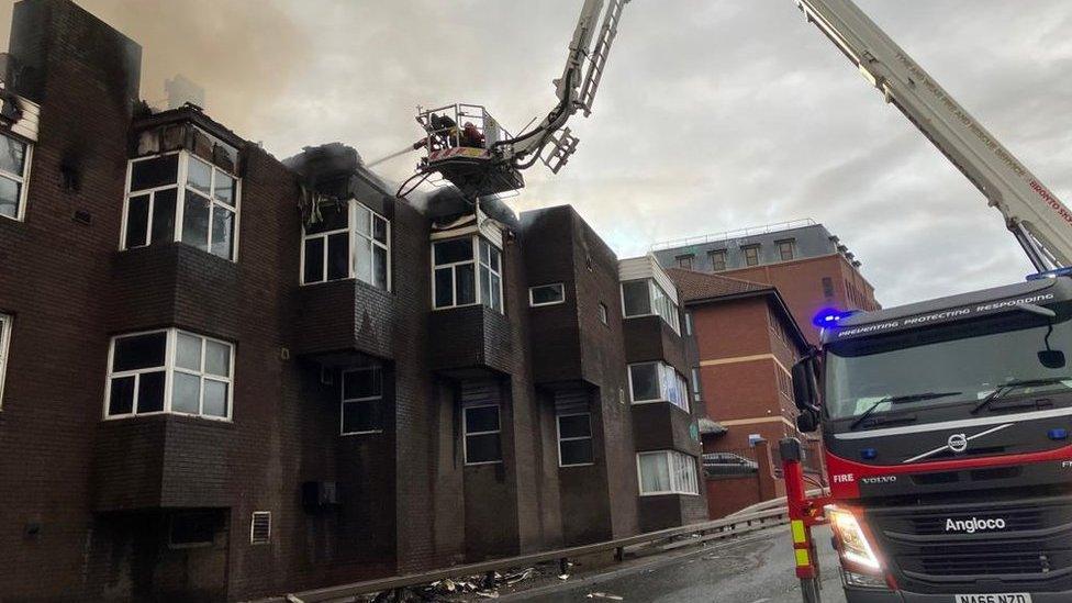 Firefighters on a crane platform extinguish the blaze at Carliol Square