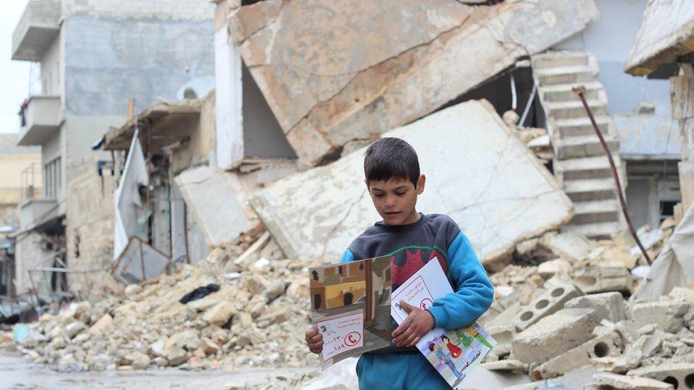 A child carries manuals distributed by Unicef volunteers on identifying and reporting unexploded objects in al- Sakhoor neighbourhood of eastern Aleppo, Syria