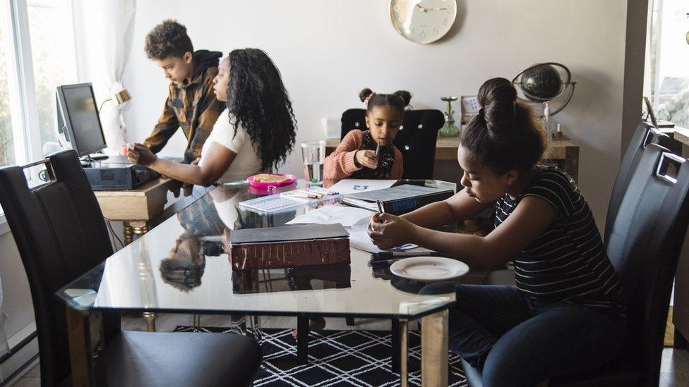 children-doing-homework-and-mother-working-in-small-space.