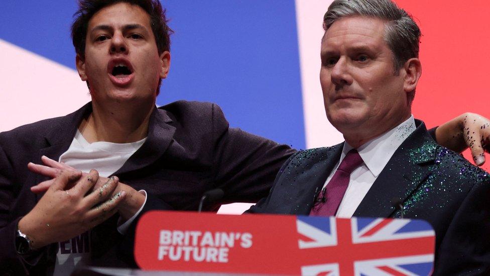 A protester throws glitter at Britain's Labour Party Leader Keir Starmer at Britain's Labour Party annual conferenc