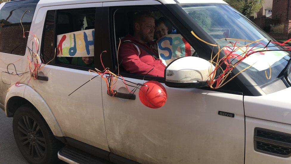 Car decorated with birthday banners and balloons.