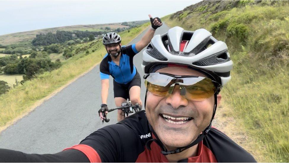 Two men cycle on a country road