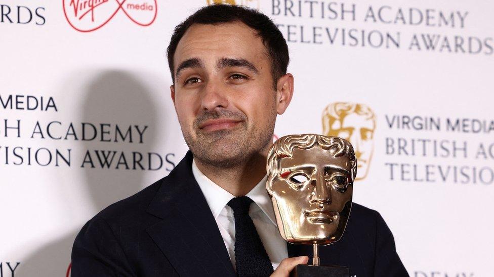 Jamie Demetriou holding his Bafta Award