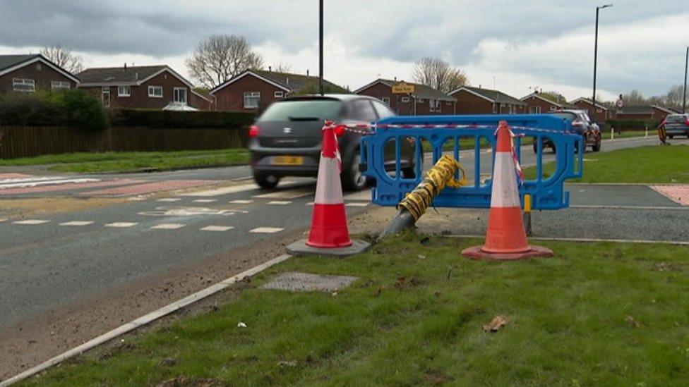 Car drives by stump of a lamppost