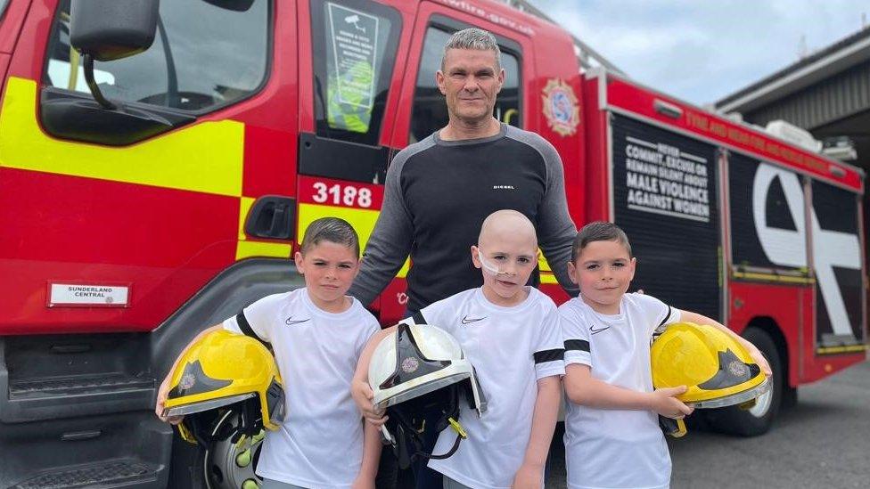 Oliver's uncle, firefighter Peter Wilson, with the triplets standing in front of a fire engine