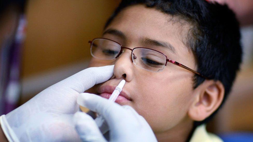 Child getting vaccine spray