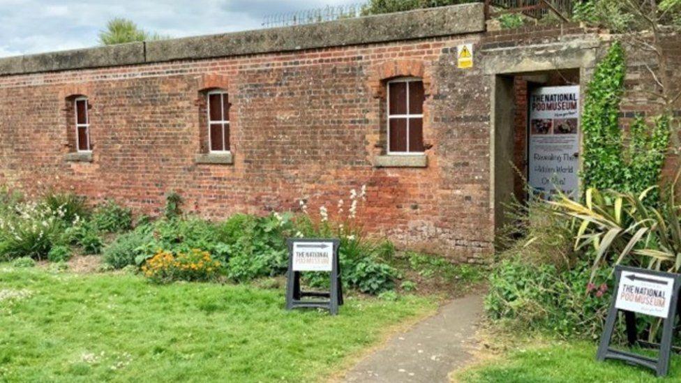 One storey brick building with three windows and a door with A-frame signs outside.