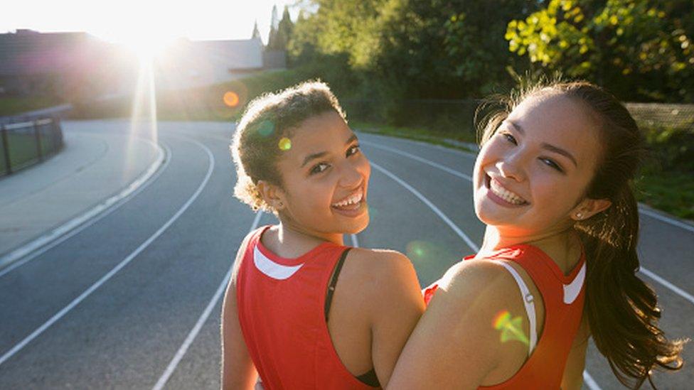 two girls looking back on a race track smiling