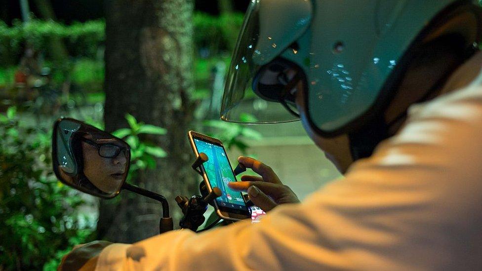 Motorcyclists play Pokemon Go on their smartphones on August 7, 2016 in Taipei