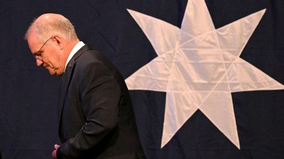 Scott Morrison walks in front of an Australian flag