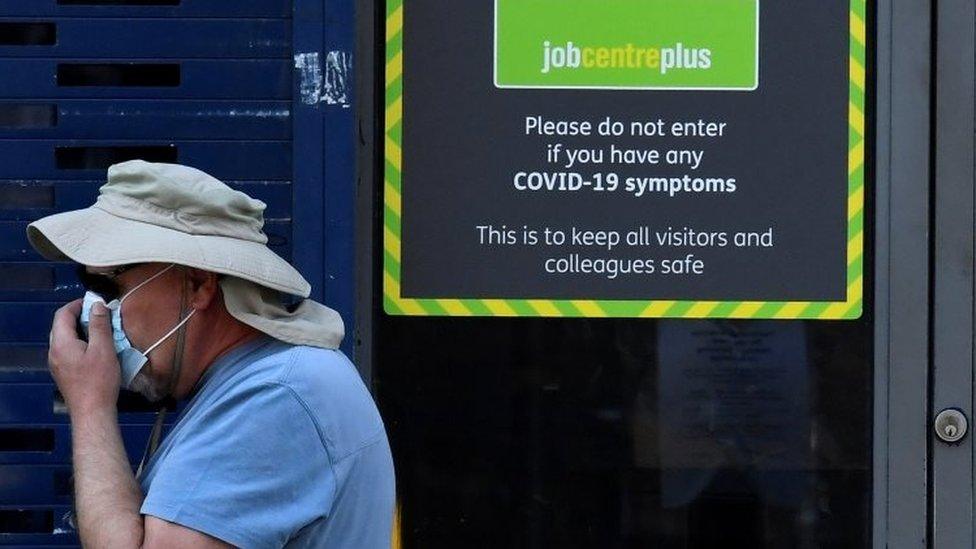 A man wearing a face mask walking past a Job Centre