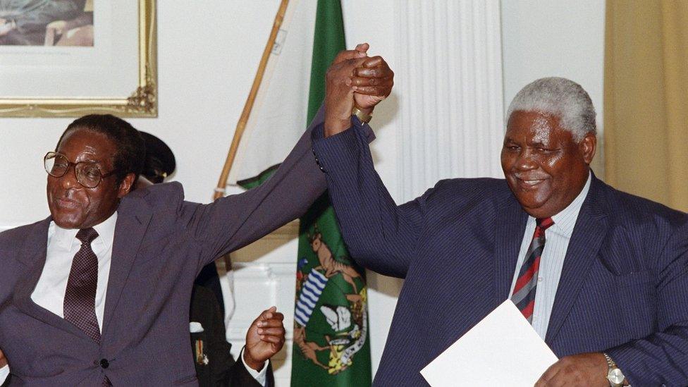 Zimbabwe's President Robert Mugabe (L) and former President of Zimbabwe African People's Union (ZAPU) Joshua Nkomo raise their fists 22 December 1987 in Nairobi.