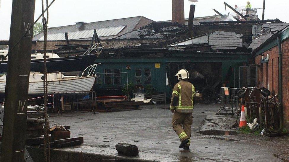 A firefighter walking through the damaged boat yard