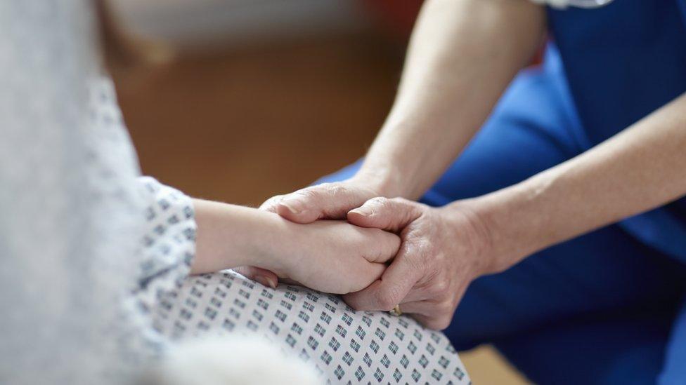 Nurse holding a patients hand