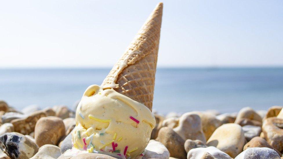 vanilla ice cream cone fallen upside down on a pebbled beach on a sunny day