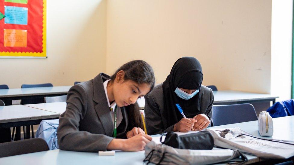 Two school pupils, one with a mask on