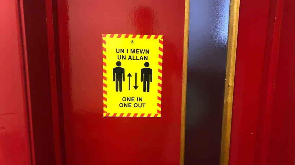 A sign on a toilet door reading 'one in, one out'