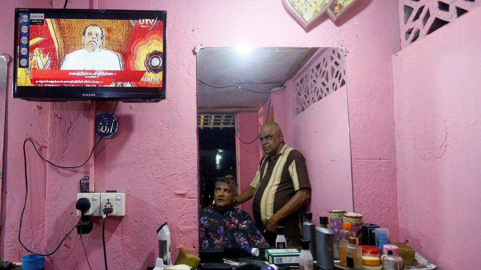 Two men watch Mr Sirisena's speech