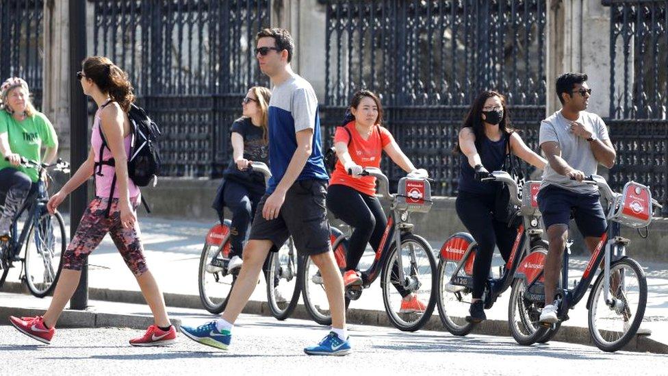 Pedestrians walk past cyclists at a red traffic light in Westminster, London