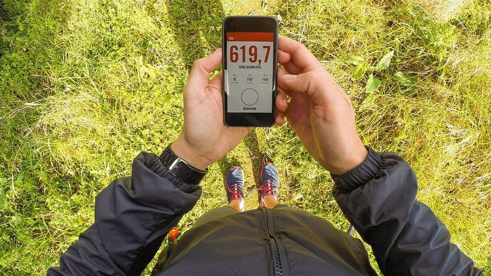 Man holding smartphone with a running app