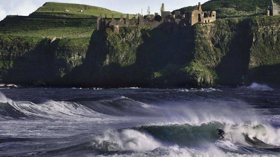 Al Mennie surfing below Dunluce Castle