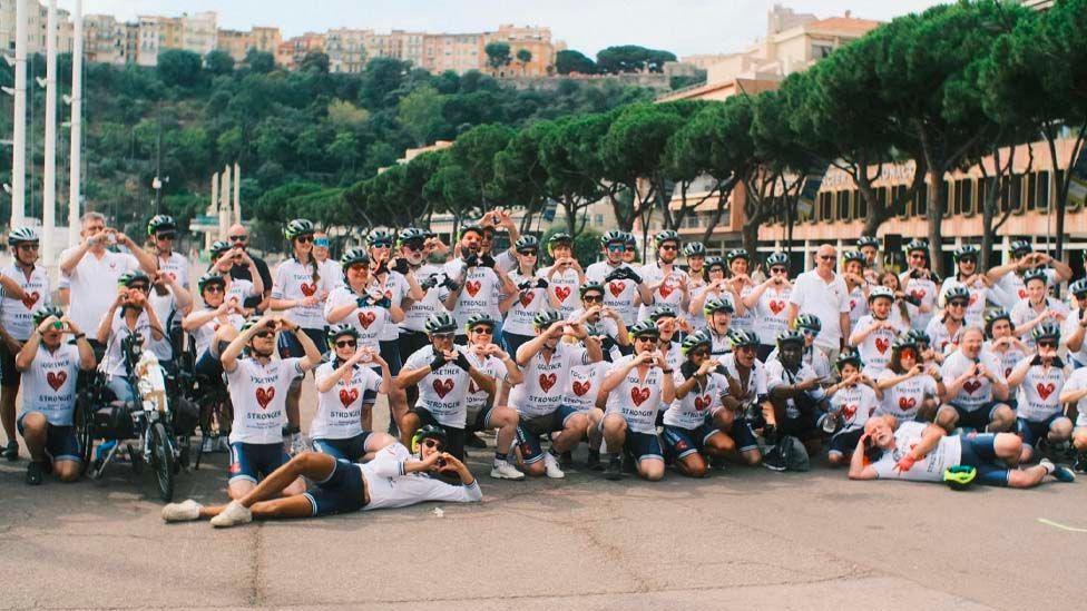 All the team who took part in the event, wearing cycling gear and making heart shapes with their hands