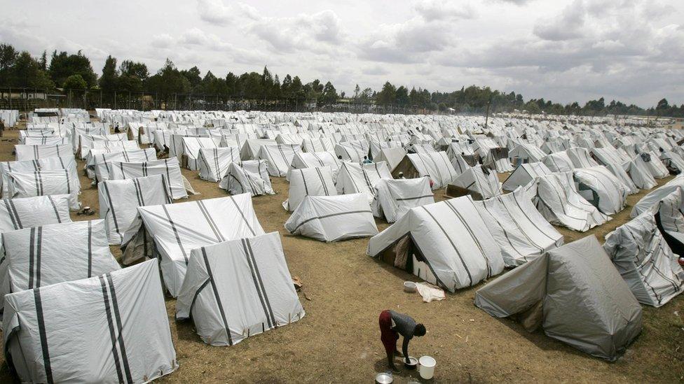 A Kenyan woman cleans utensils amid hundreds of tents set up for displaced people at the Eldoret Show Grounds (1 February 2008)