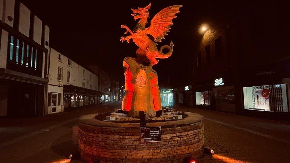 a dragon sculpture on a high street illuminated orange