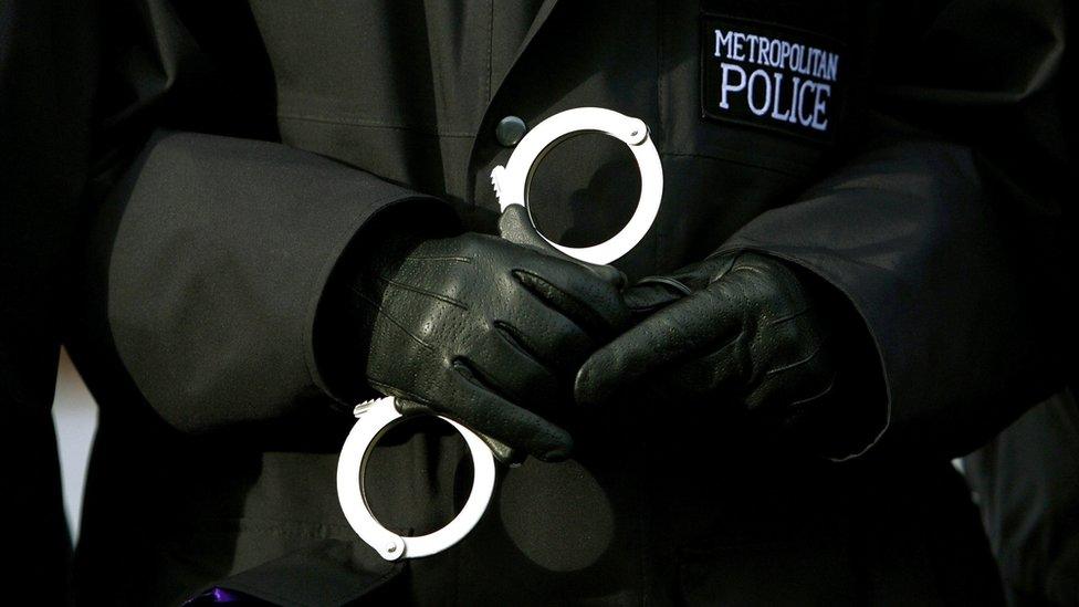 Met Police officer holding a pair of handcuffs