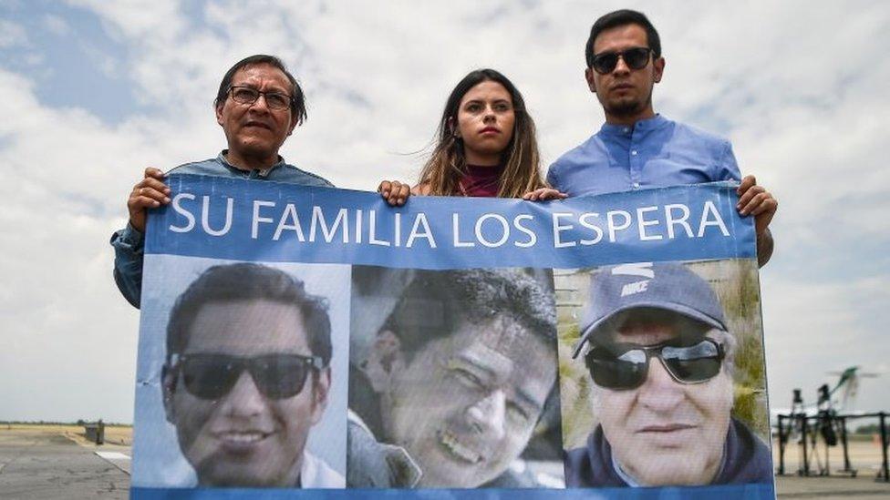 Ecuadorean El Comercio journalist Javier Ortega's father, Galo Ortega (L), photographer Paul Rivas's daughter, Carolina Rivas (C), and driver Efrain Segarra's son, Cristian Segarra (R), hold a banner with their portraits at Alfonso Bonilla Aragon airport in Palmira, Colombia, on June 22, 2018