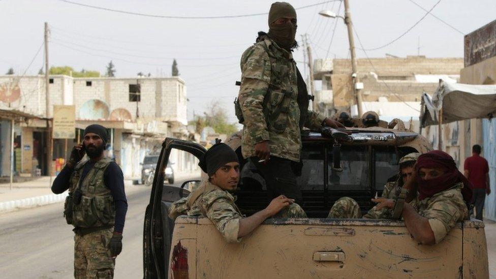 Turkish-backed Syrian fighters sit in the back of a truck in the Syrian border town of Tal Abyad on October 17, 2019