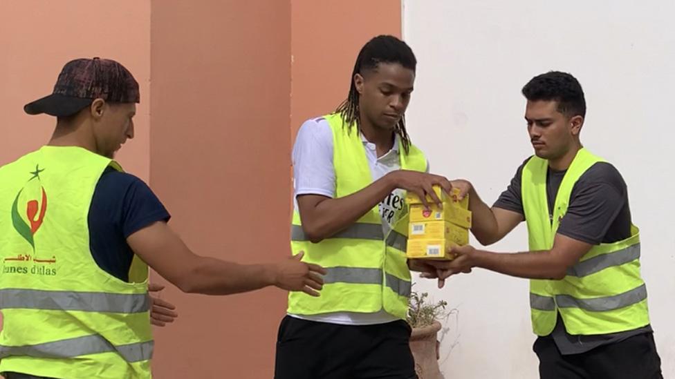 A group of young volunteers pass aid parcels to each other