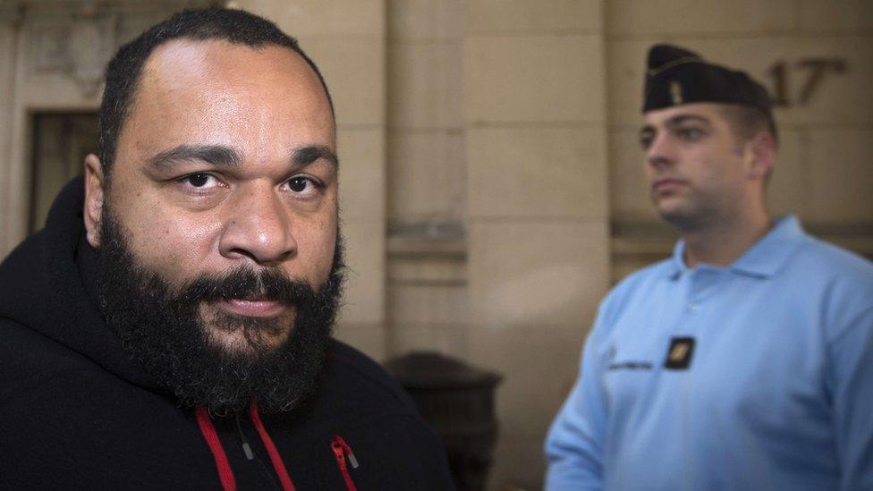 French controversial humorist Dieudonne M'bala M'bala arriving for trial at a Paris courthouse on the charges of defamation, insults, incentive to hate and discrimination on 13 December 2013