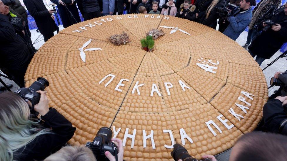 People gathering around a traditional Serbian Christmas bread on Orthodox Christmas Day