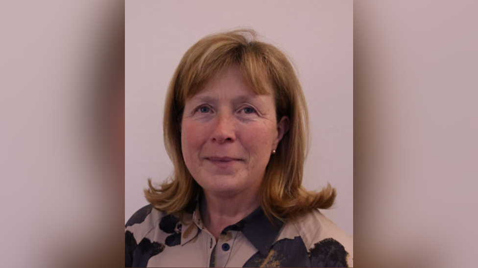 Oireachtas picture of Gillian Toole. She has strawberry blonde shoulder length hair curled at the bottom and a fringe. She is wearing a beige and black shirt and gold ball earrings.
