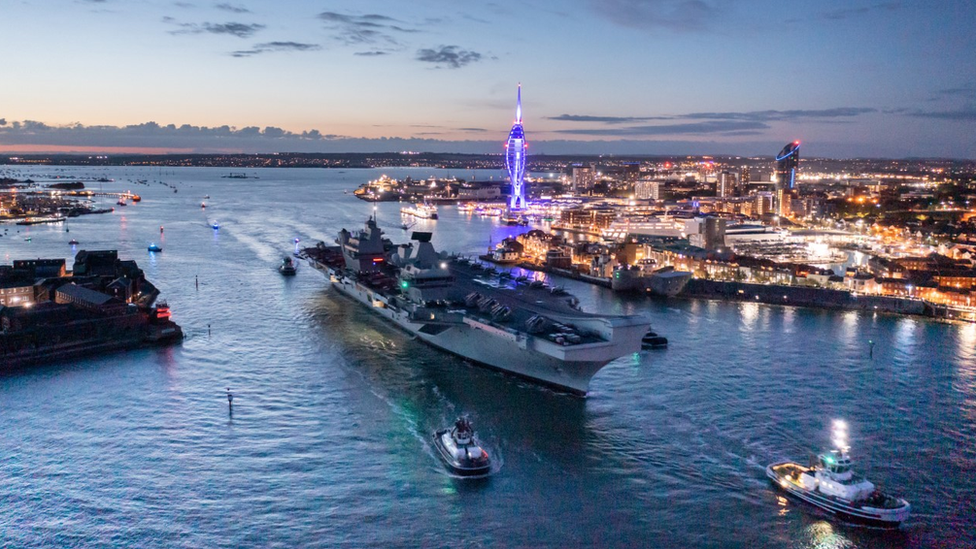 HMS Queen Elizabeth departs the bright lights of Portsmouth