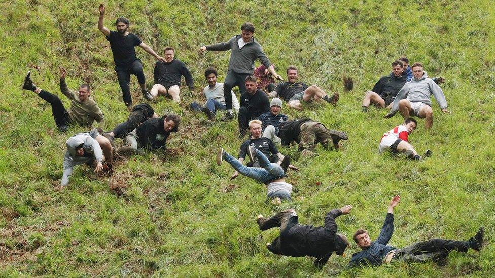 People falling in various poses down Coopers Hill in Gloucestershire