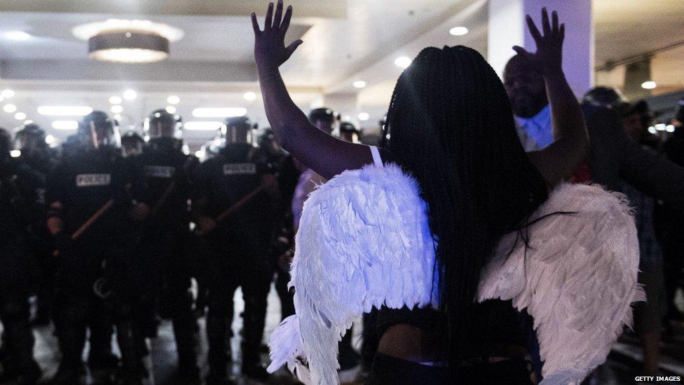 A woman stands in front of a police line