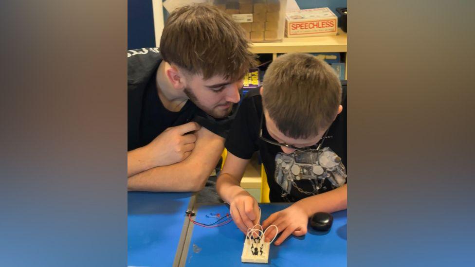 Charlie helping a boy with an electric circuit