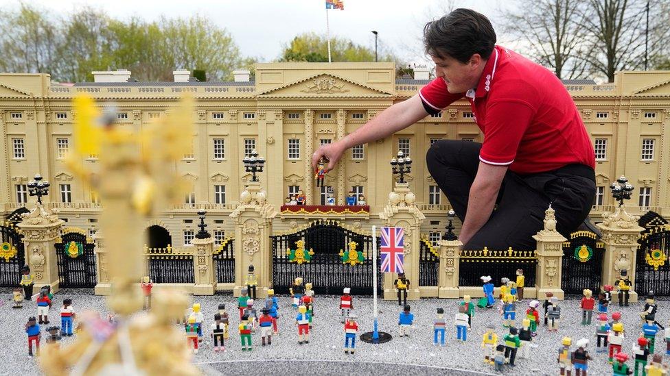 Model maker Daniel Anderson from the Legoland Windsor Resort, places a Lego model of King Charles III onto the balcony of Buckingham Palace as part of a coronation miniland scene