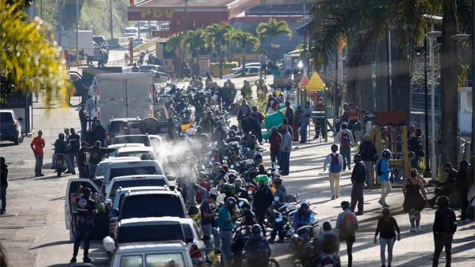 People are seen beside cars parked in line to refill gasoline in San Antonio, near Caracas, Venezuela September 9, 2020