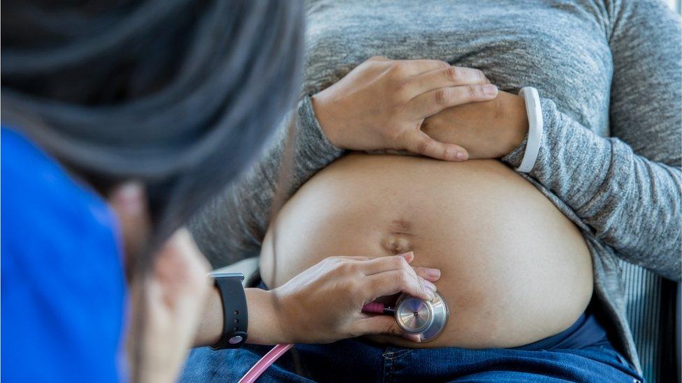 A health professional examining a pregnant stomach