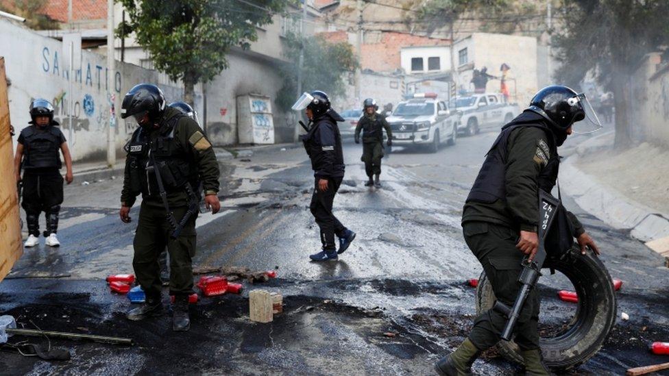 Members of the security forces remove debris from a barricade as they patrol the streets in La Paz