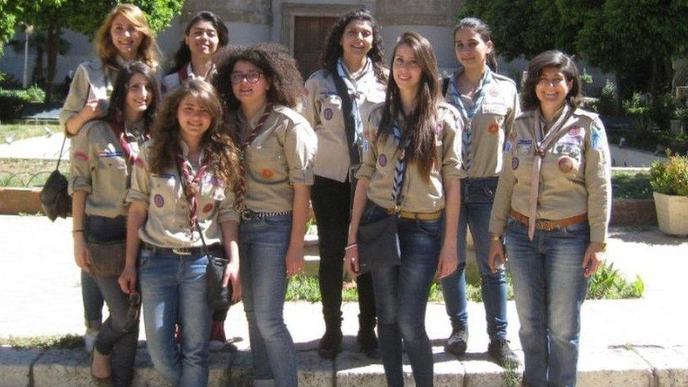 Nine girl guides in uniform on the pavement in the sunshine